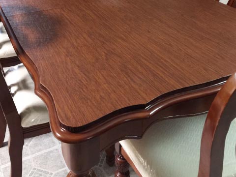 Table protector with custom shaped edge in cherry woodgrain