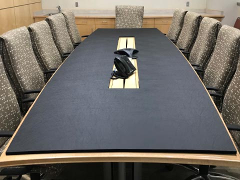 Conference room table pad with cutouts for phones and cables